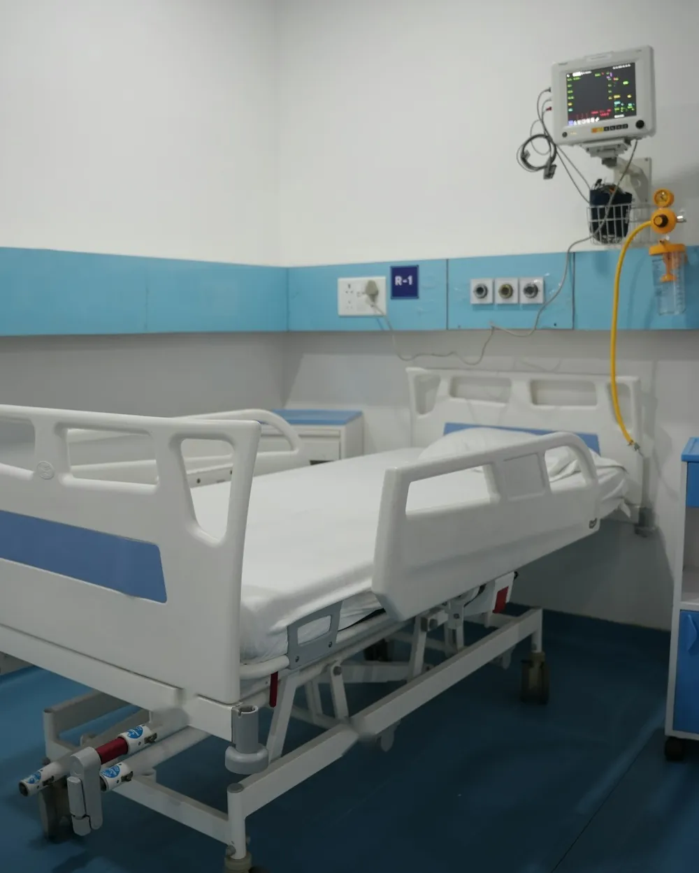 ICU bed space with electric hospital bed, bedside locker and patient monitor